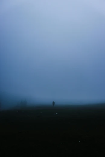 lone man walking in dark, foggy landscape