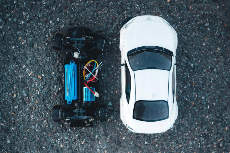 top down view of an electric car on the ground and a white toy car