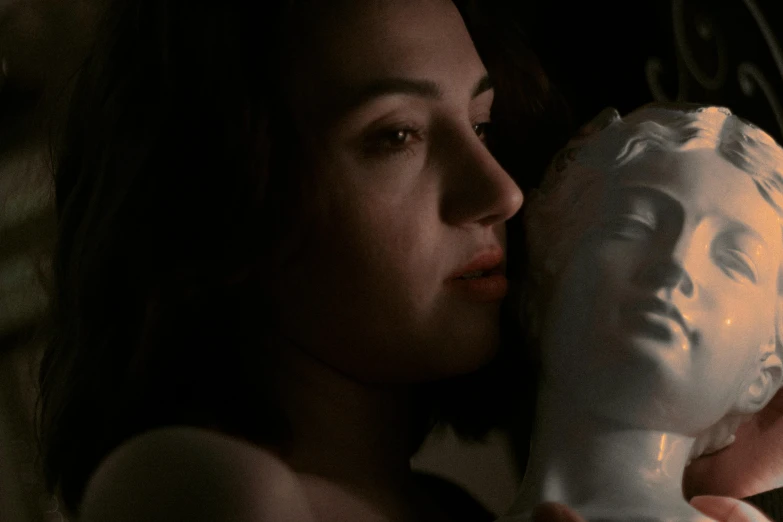 a girl holding a statue in her hand next to a light