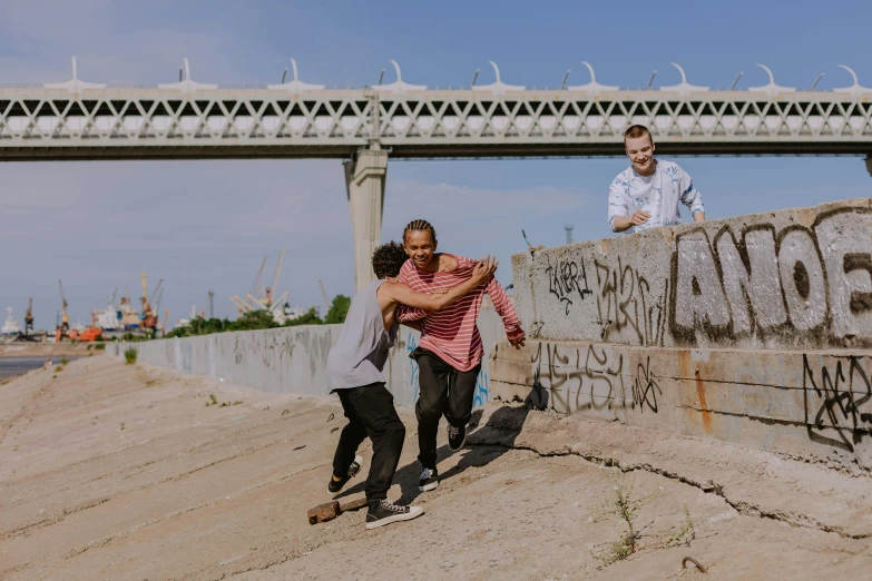 a man holds another man's arm while they both pose with graffiti