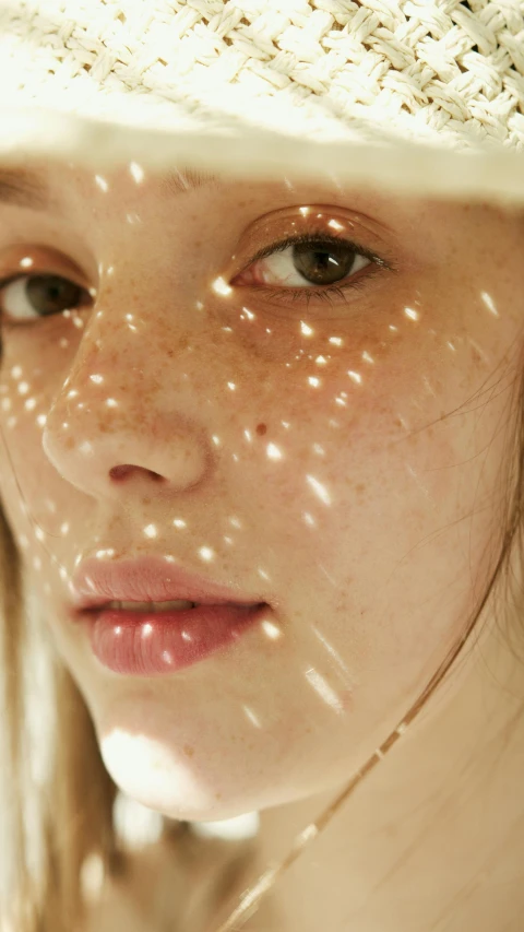 a lady wearing a straw hat has bright spots on her face