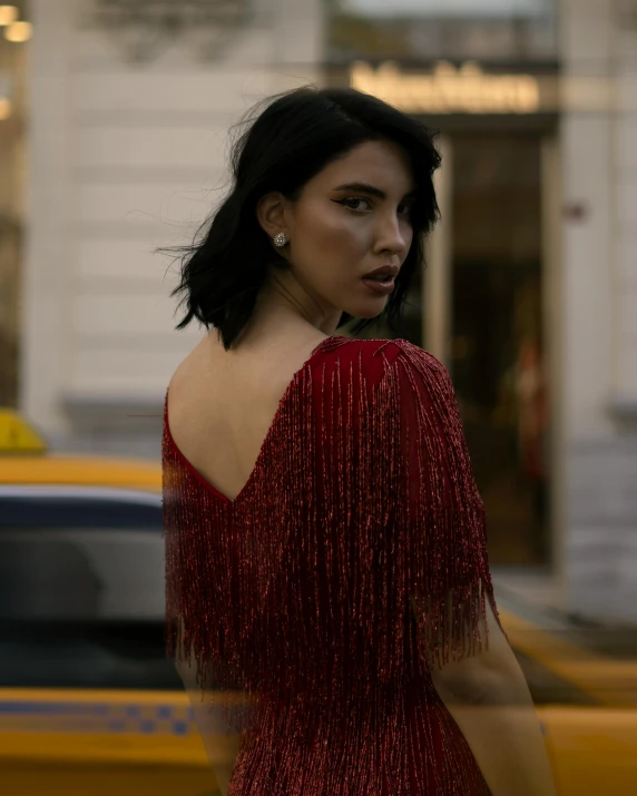 a woman in a red dress walks by a taxi