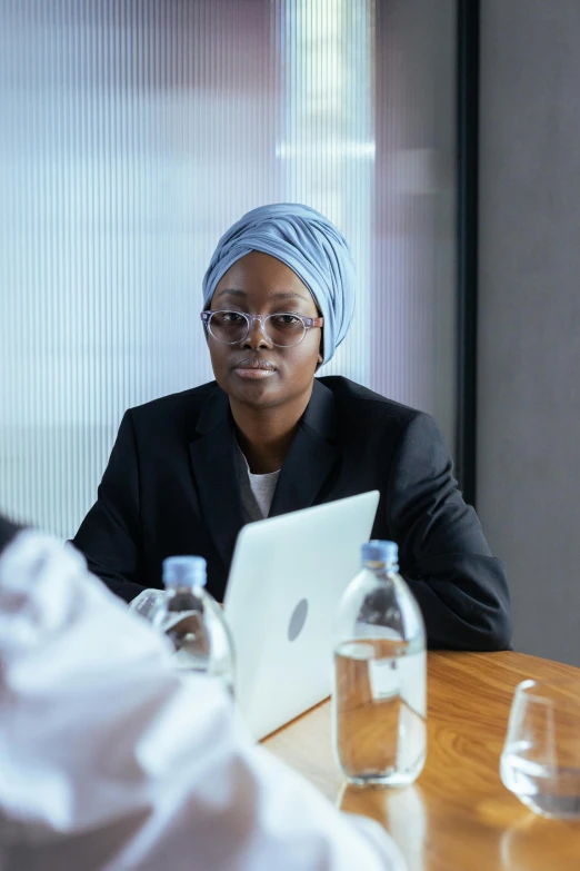 a woman in a head scarf sits at a desk with an ipad in front of her