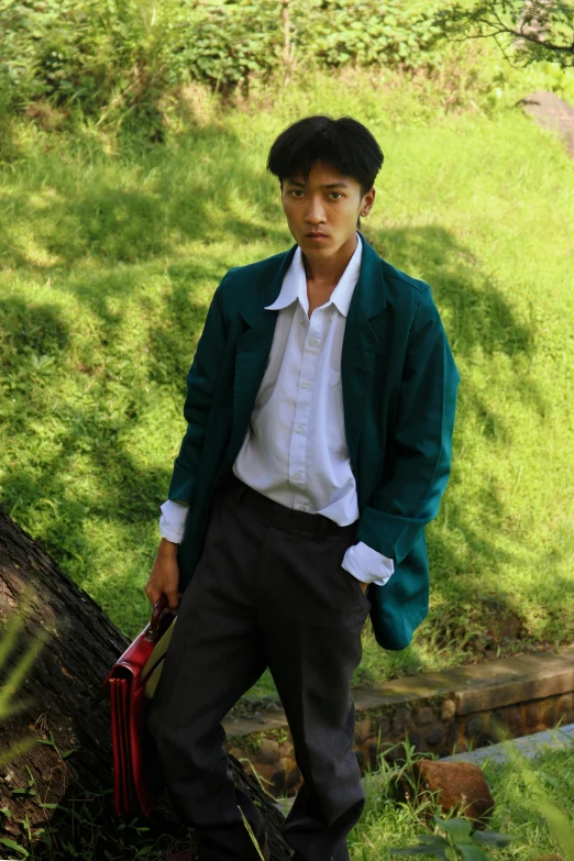 young man standing by tree in uniform with briefcase