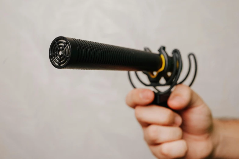 a black and yellow microphone being held in the palm of a hand