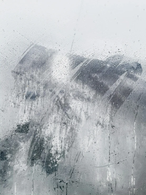 drops of rain cover the windshield of a car in a car park