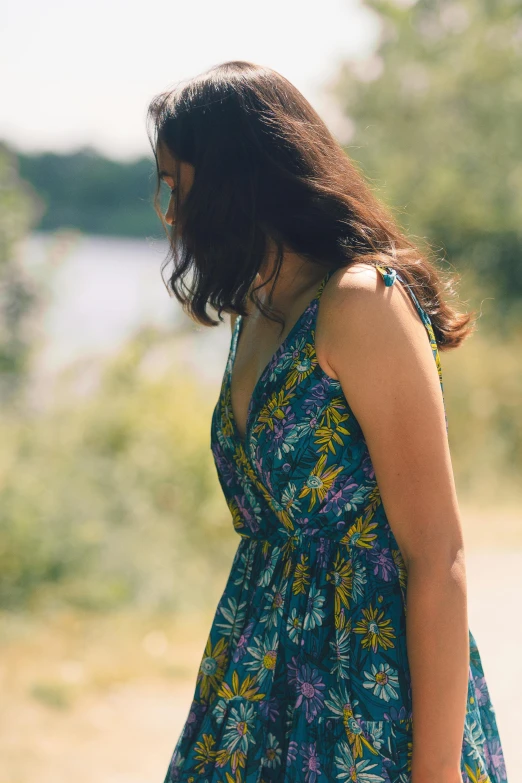 a woman is standing in the grass wearing a floral dress