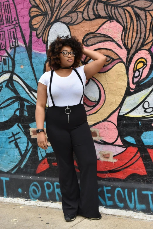 woman with glasses standing in front of wall with colorful graffiti