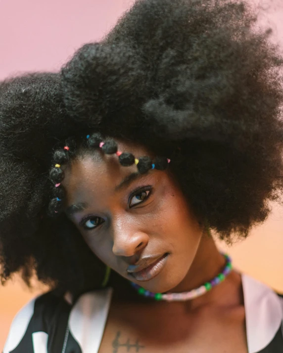 a woman with a fake afro is wearing a multi - colored celet