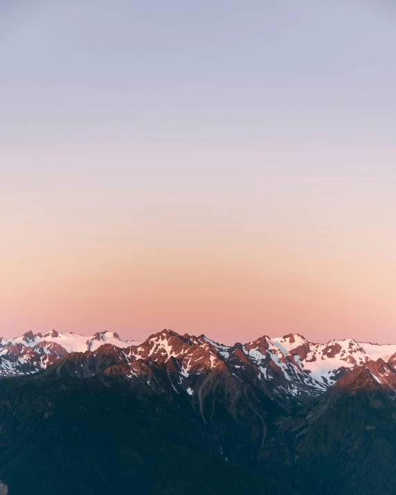 a pink sky with snow on the mountains in the distance