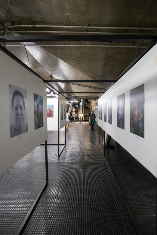 people are walking down the corridor between two white walls