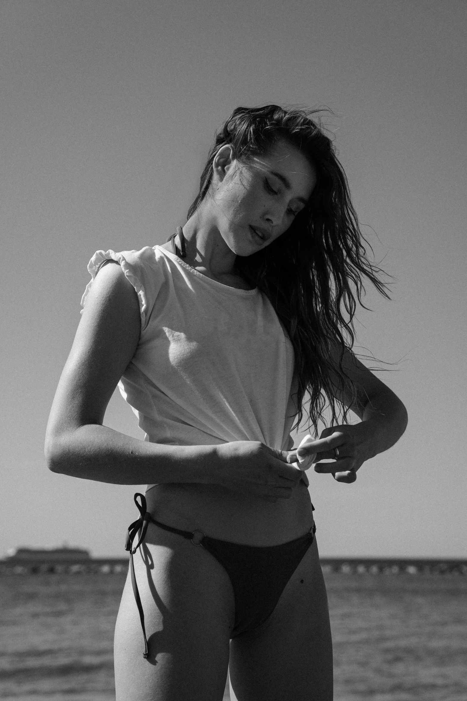 a young lady is standing on the beach in a bikini