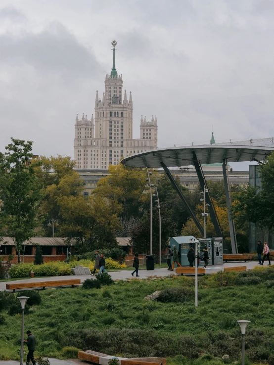 people are walking around in a park near an outdoor area with benches and umbrellas