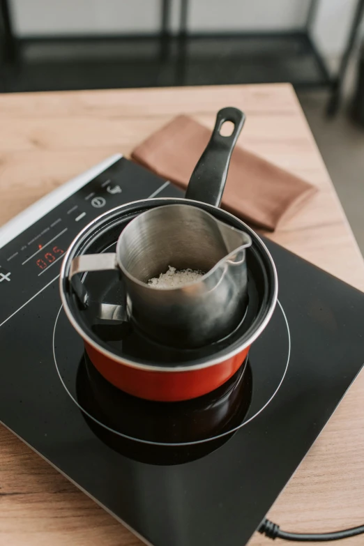 a pot sitting on a stove top holding a  cup