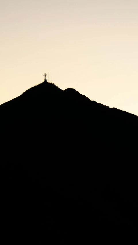 the sun setting behind the mountain top, with the peak and spire visible