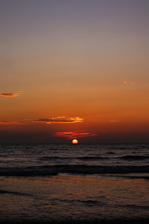 the sun is setting over the ocean at dusk