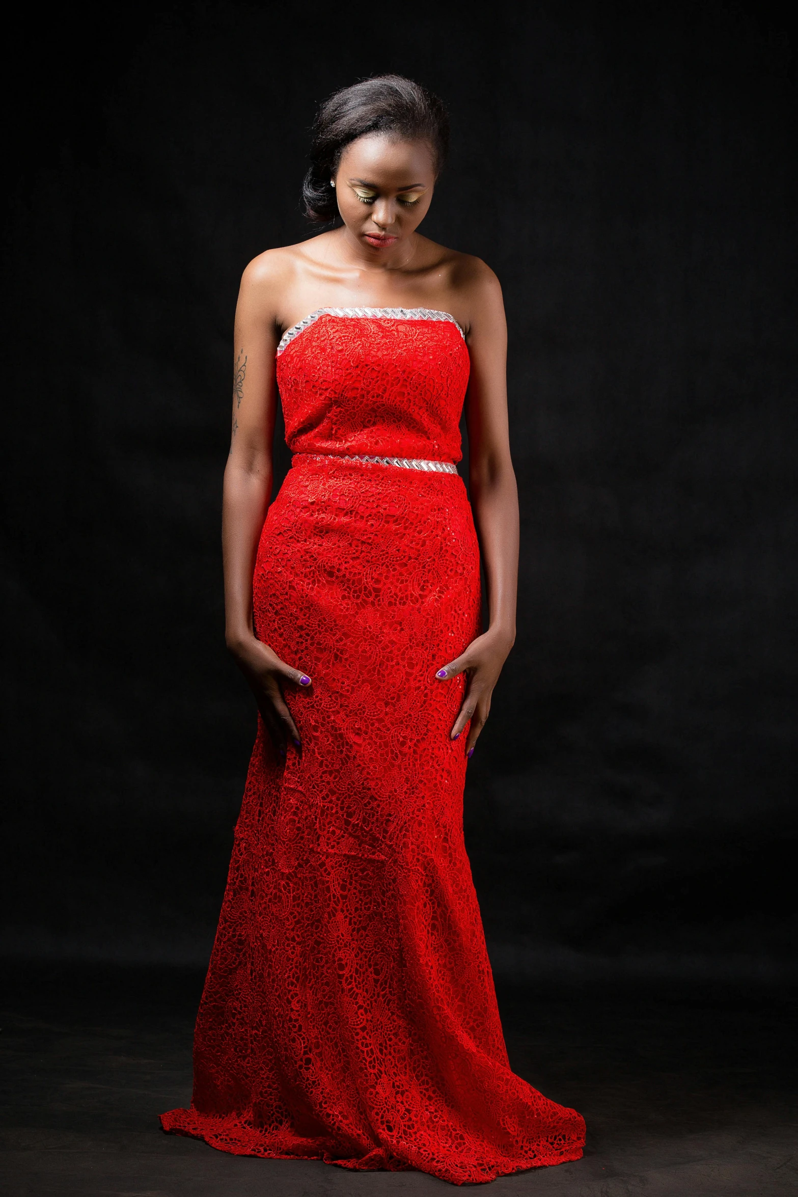 a young woman is standing in a long red dress