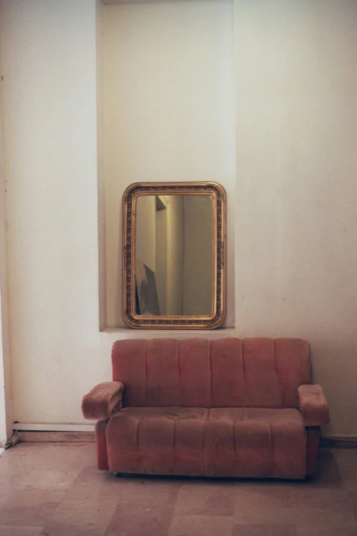 the sofa and mirror are placed near a wall