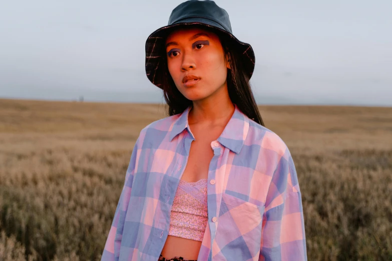 a woman in a hat is standing in a field