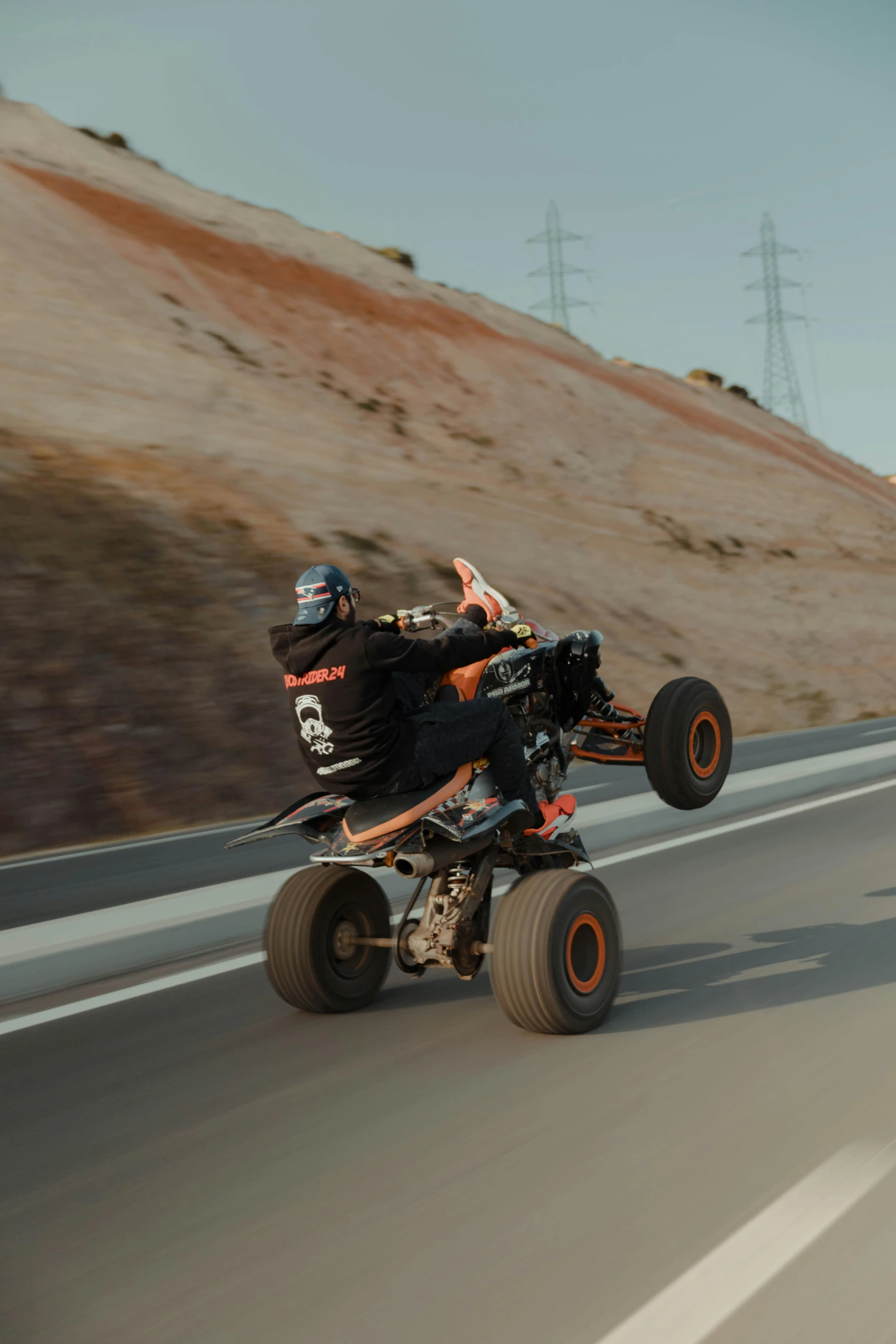 two people riding on four - wheeled vehicle down the road