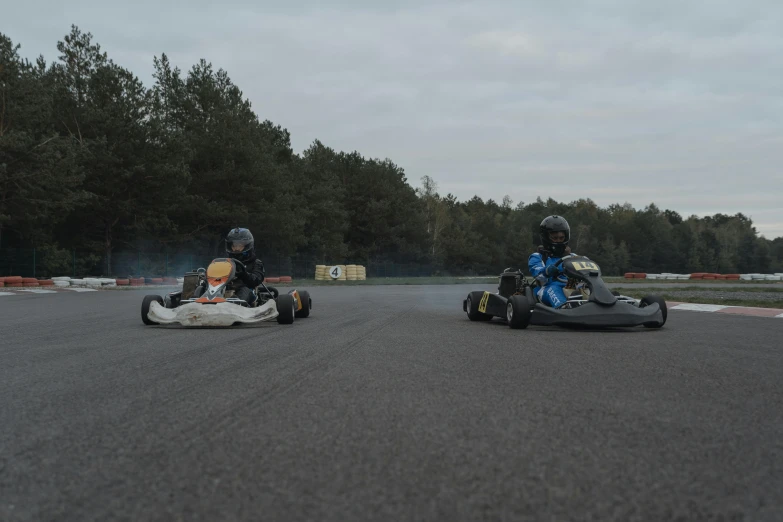 two s riding bumper cars down an empty race track