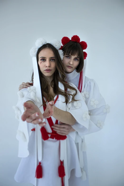 two beautiful women in white dresses holding an object