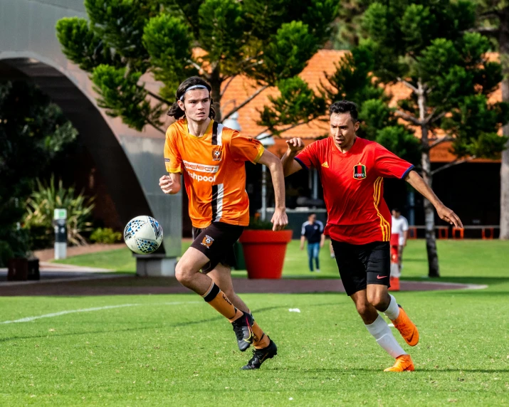 two young men run after a soccer ball