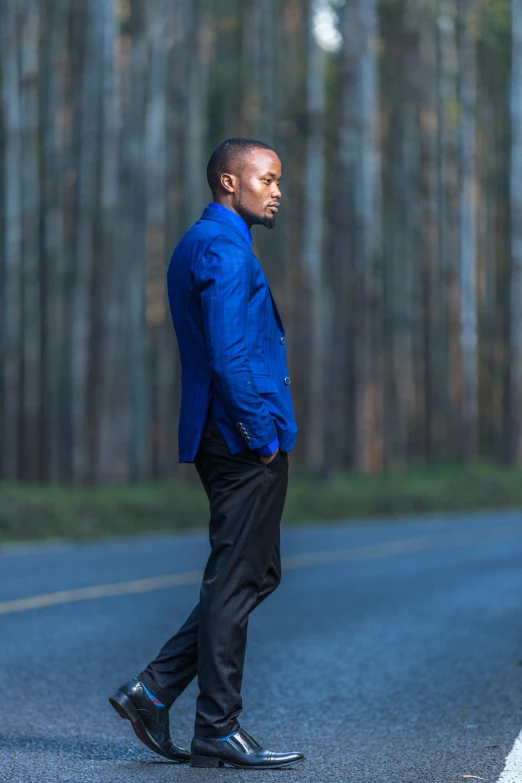 a man standing on the side of a road next to a forest