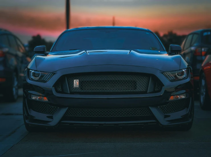 a black mustang on a dark street with other cars