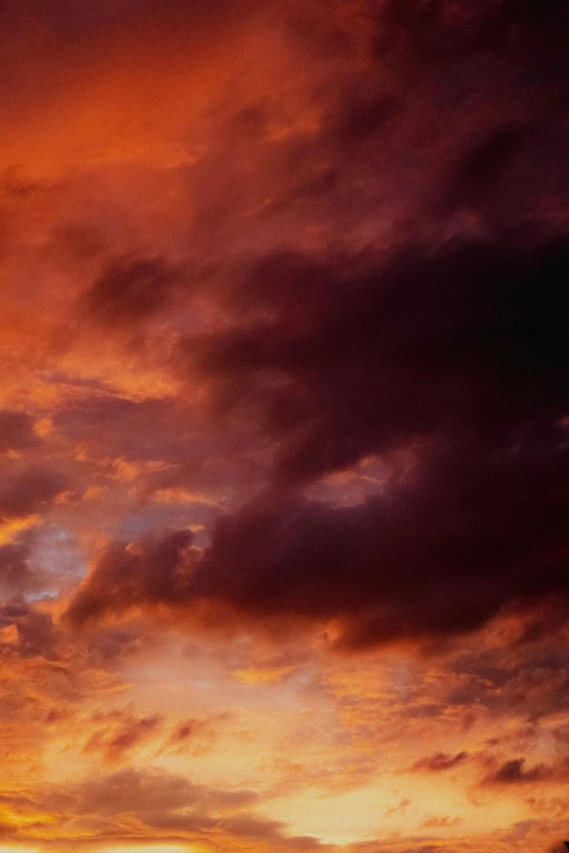 an orange and red sky with clouds in the distance