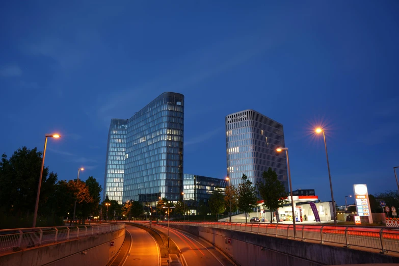 two large buildings near a roadway and traffic lights at night