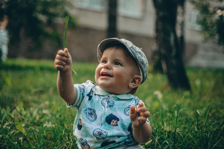 a  sitting in the grass while holding a piece of green plant