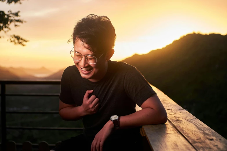 a young man sitting down in the sunset