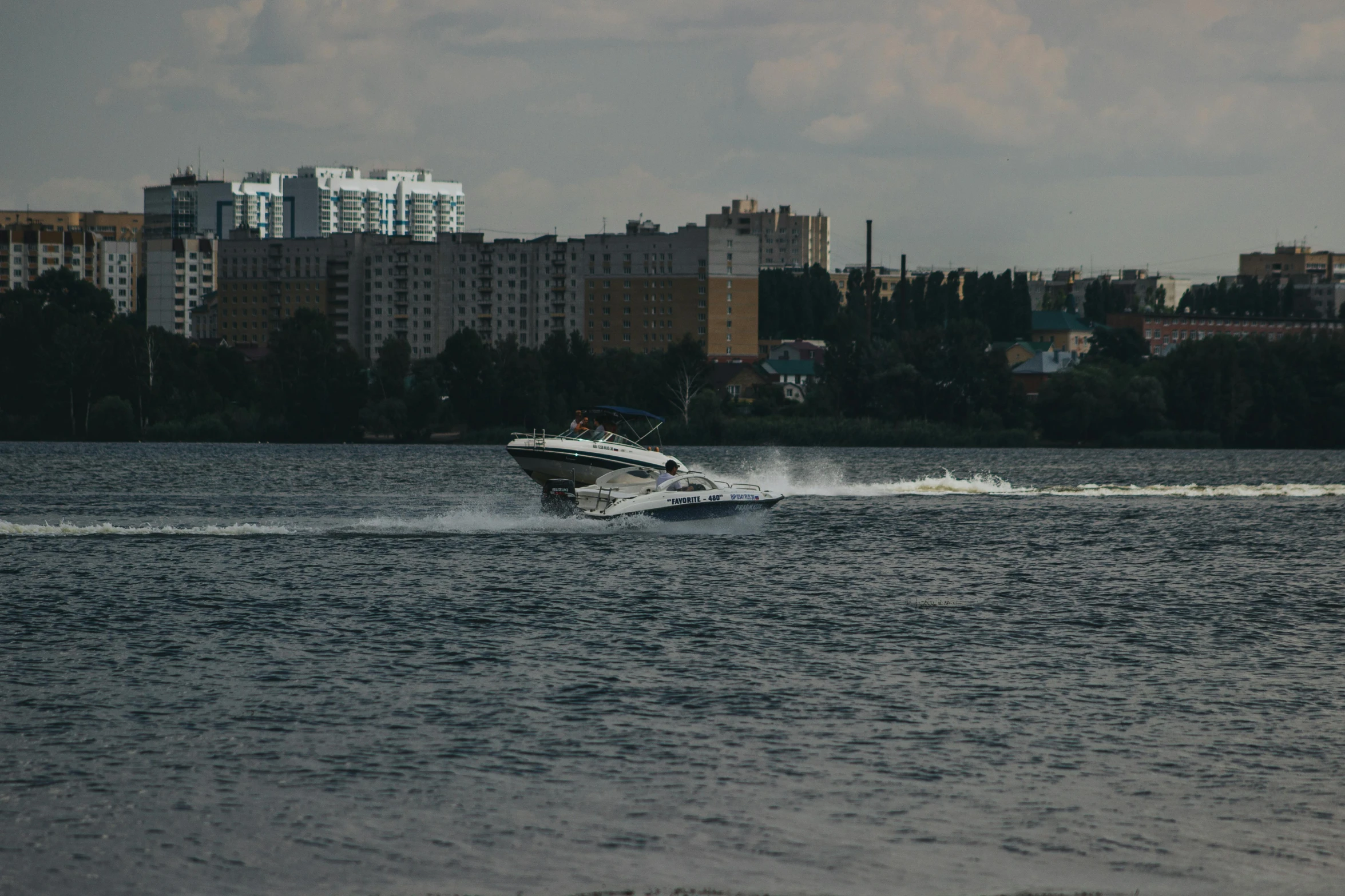 a small boat glides across the water in front of the city skyline