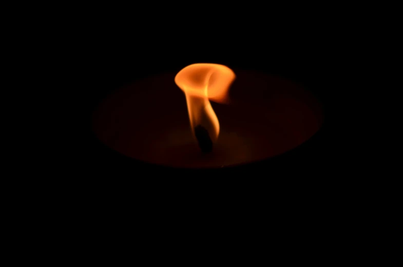 a candle on a plate with the reflection of a large candle