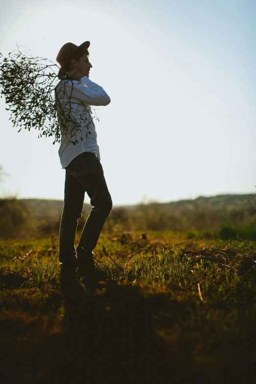 there is a man holding a leafy tree