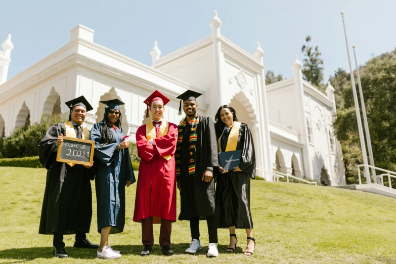 three people standing outside a church wearing their graduation gowns