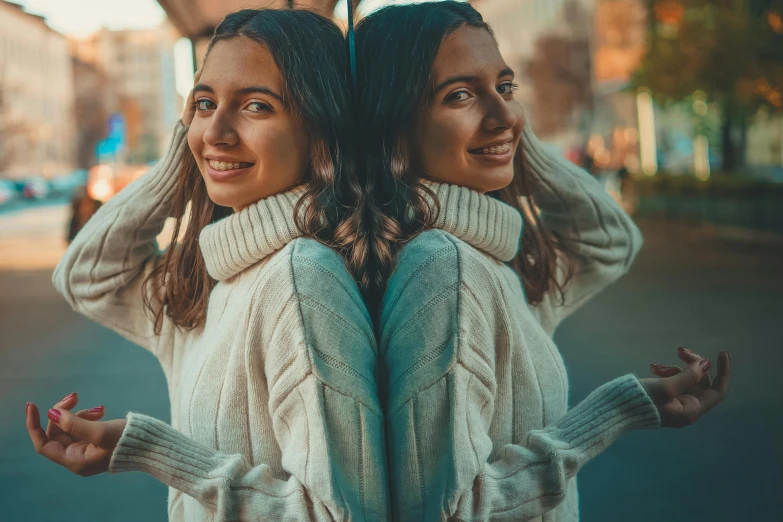 two girls smiling and standing together in a city street