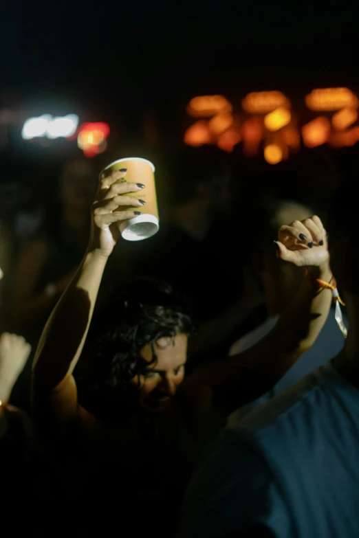 a crowd is holding up cups in the dark