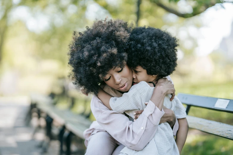 two young women hugging each other on a bench