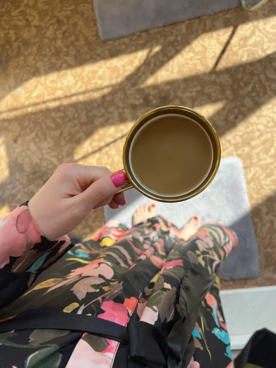 woman holding up a cup of coffee in her hand