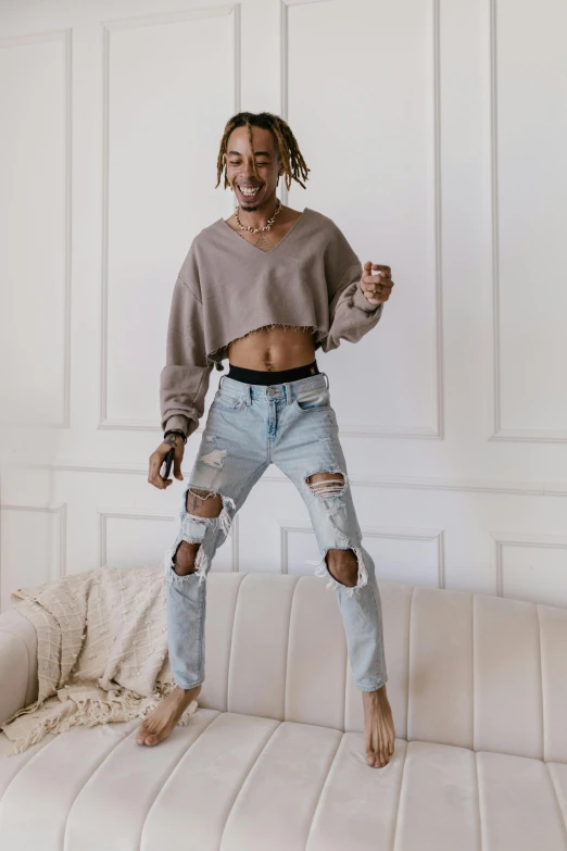 a woman with ripped jeans and sweater posing on a couch