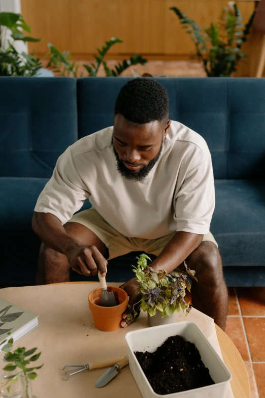 a man sitting in front of a table that has two potted plants on it