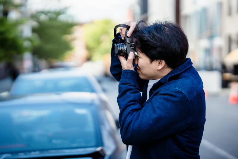 a man is taking pictures on a phone while he stands near a car