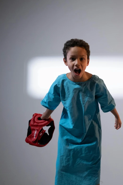 a little boy with a baseball mitt standing in front of a light