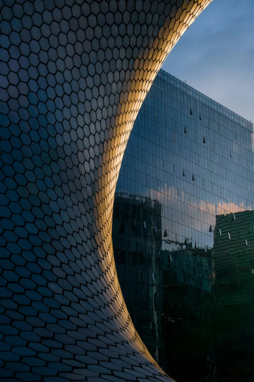 a modern building with a glass facade reflecting the sky