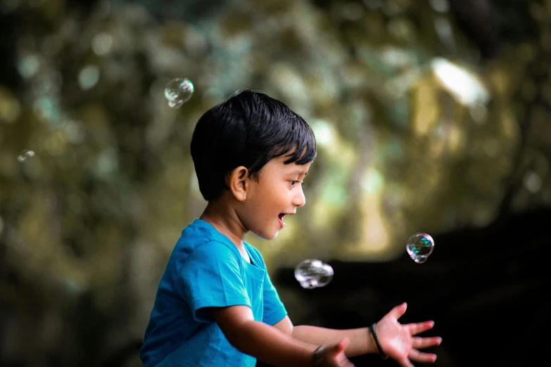 a little boy in a blue shirt is trying to catch a frisbee