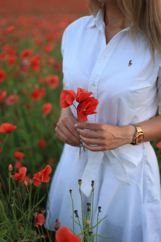 a woman standing in a field with flowers in her hands