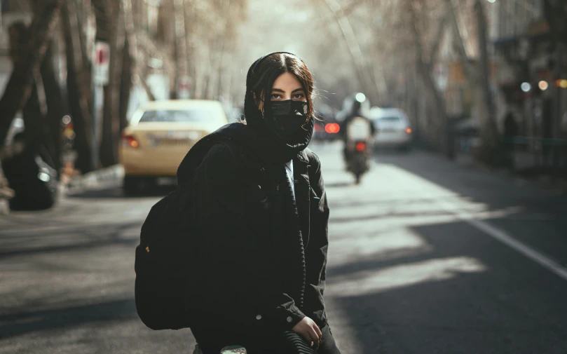 a woman wearing a mask walking down a street
