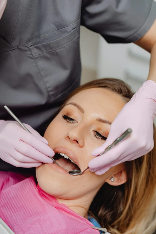 a beautiful woman is getting her teeth brushed